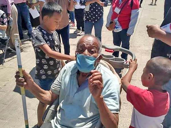 Niños usan carriola para llevar a su abuelito a vacunar