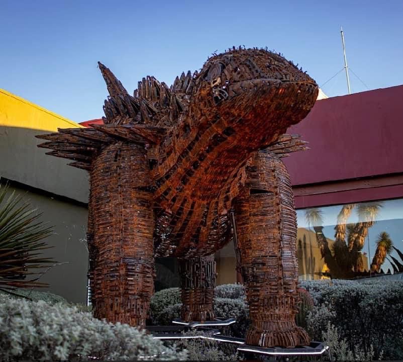 Crean escultura de dinosaurio con armas