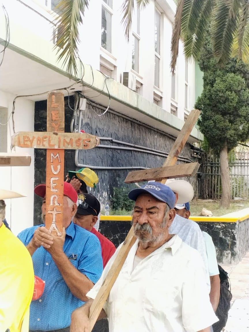 Jubilados cargan cruces y exigen pensión digna